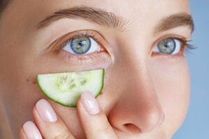 Beauty portrait of young woman moisturizing skin around eyes